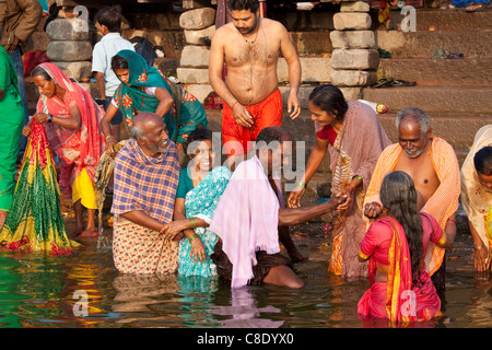 Women washing clothes on the ghats of the River Mahanadi, reflected in ...