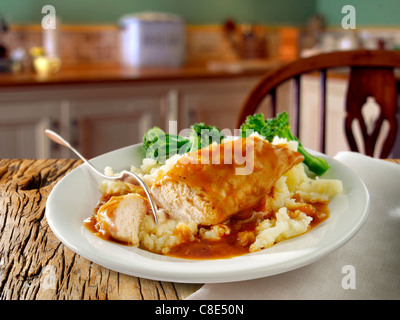 Traditional roast chicken dinner served on a plate on a wood table in a kitchen setting Stock Photo