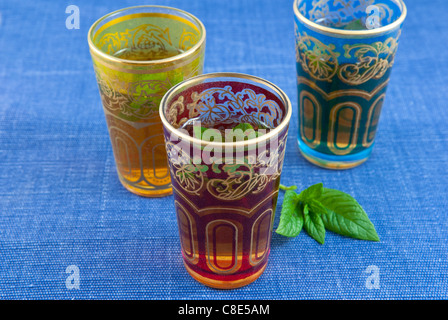 Small coloured glasses of mint tea on a blue background . Stock Photo