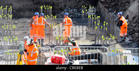Health & safety construction building site hard hat workers steel reinforcement rods with yellow safety caps to reduce accidents  Stratford London UK Stock Photo