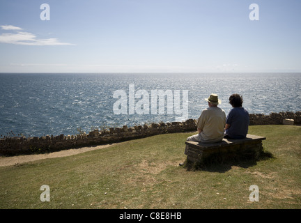 Couple sitting on bench admiring the coastal view from the Isle of Purbeck, Dorset, England UK Stock Photo
