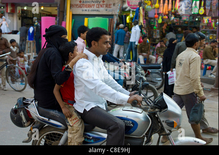 Young Indian Muslim family ride motorcycle in street scene in city of Varanasi, Benares, Northern India Stock Photo