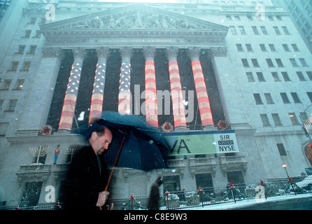 Wall Street workers and visitors pass the New York Stock Exchange, decorated for Christmas in the snow Stock Photo