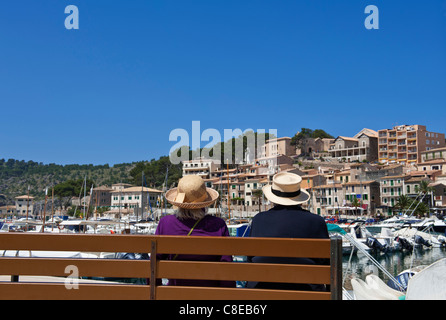 Spanish vacation holiday older ladies with straw sun hats sitting on bench together enjoying the harbour view Port de Soller Palma de Mallorca Spain Stock Photo