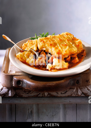 Traditional hot cooked British Cumberland potato and meat pie served on a plate in a kitchen setting ready to eat Stock Photo