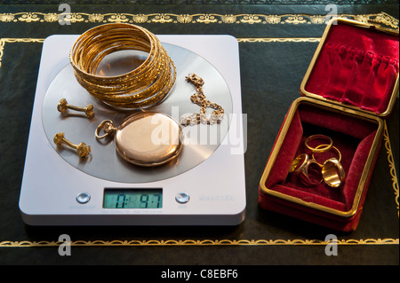 Weighing selection of gold jewellery on portable digital desk weighing machine displaying weight in ounces Stock Photo