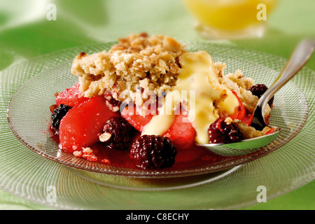 British Food - Blackberry & Apple Crumble and custard served and ready to eat Stock Photo
