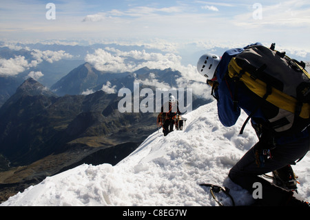 A photographer taking pictures as a team of climbers reach the summit of a peak in the alps Stock Photo