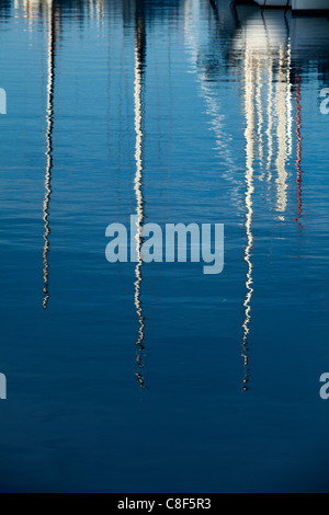 Yacht masts reflected in the water of Talamone harbour. Tuscany, Italy. Stock Photo