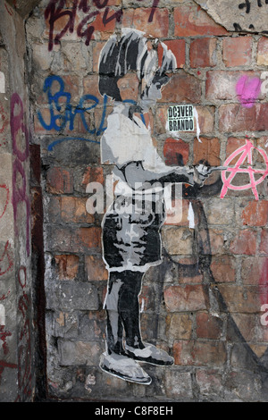 Graffiti on brick wall, showing small child begging and anarchy symbol, Berlin, Germany Europe Stock Photo