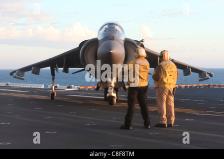 Navy flight deck crewmen direct an AV-8B Harrier jet on the flight deck of the USS Bonhomme Richard, Stock Photo