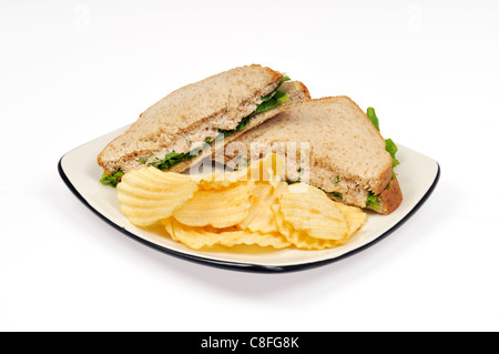 Tuna mayo with lettuce on wholemeal bread sandwich with potato chips on white plate on white background cutout. Stock Photo