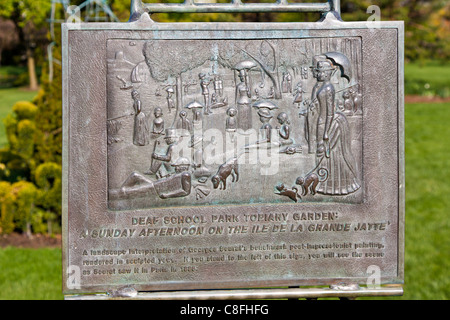 Plaque at entrance to the Old Deaf School Topiary Park in Columbus, Ohio shows the painting that was the model for the park. Stock Photo