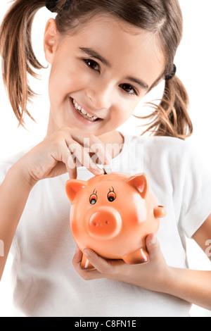 Little girl holding a piggy-bank and inserting a one euro coin Stock Photo