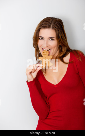 Beautiful young woman bitting a gingerbread cookie Stock Photo