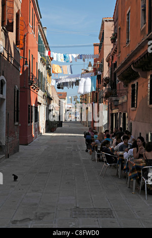 Clothes washing hanging out to dry above street cafe, Venice Italy Stock Photo