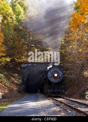 Old steam train pulling out of a tunnel belching steam and smoke Stock Photo