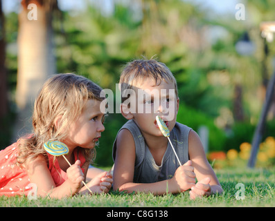Two children with lollipops in tropical garden Stock Photo