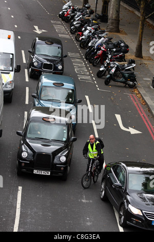 Looking down on traffic traveling along a road in London and a cyclist weaving through Stock Photo