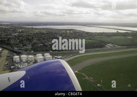 View from passenger jet aircraft window at  take off with engine in foreground and land with fields and roads below Stock Photo