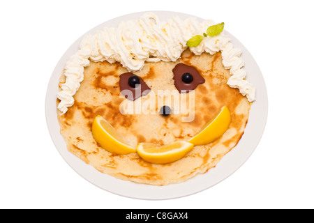 Happy face made up from crepe, lemons, blueberries, chocolate, mint and cream, isolated on white background. Stock Photo