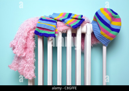 Photo of a girls hat, scarf and gloves drying on an old traditional cast iron radiator, good image for winter related themes. Stock Photo