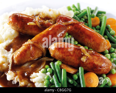 Traditional cooked Sausage and mash served on a white plate in a table setting ready to eat Stock Photo