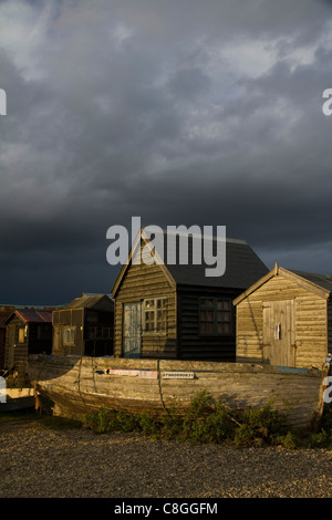 Wooden huts and boats under stormy skies on an autumn evening at Southwold Harbour, Suffolk Stock Photo