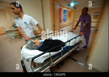 Motion blurred dynamic photo of healthcare professionals moving an old woman on a gurney in an hospital Stock Photo