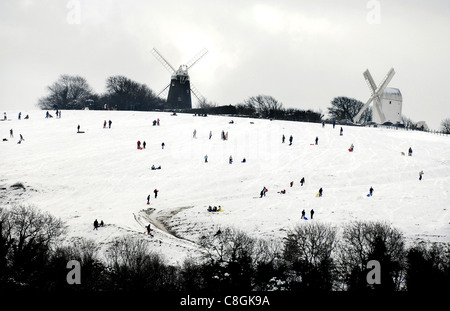 Human figures dot the hillside below Jack and Jill Windmills at Clayton in Sussex as they enjoy the snow UK Stock Photo