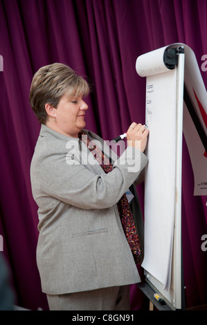 A business woman writing notes on a flip chart at a meeting presentation seminar, UK Stock Photo