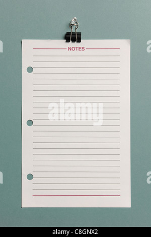 Paper with lines hanging from a clip isolated on a green background Stock Photo