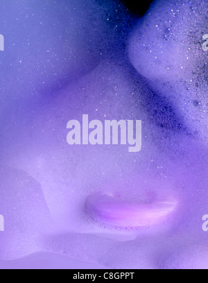 symbolic abstract background including a piece of bar soap and lots of foam in violet and blue ambiance Stock Photo