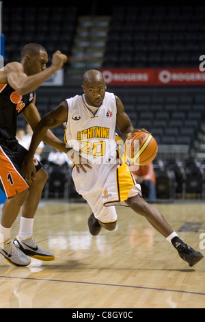 London Ontario, Canada - October 23, 2011. Eddie Smith (20) of the London Lightning drives past Josh Porter (1) of the Oshawa Power during the National Basketball League of Canada game. London won the game 111-83. Stock Photo