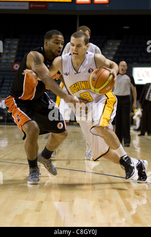 London Ontario, Canada - October 23, 2011. Nick Lother (8) of the London Lightning drives past Larry Diamond (2) of the Oshawa Power during their National Basketball League of Canada game. London won the game 111-83. Stock Photo