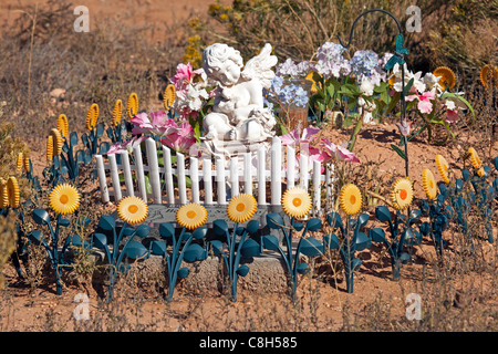 Angel and flowers and small white fence on a grave of a small girl. Old pioneer weed and neglected Fort Duchesne cemetery. Stock Photo