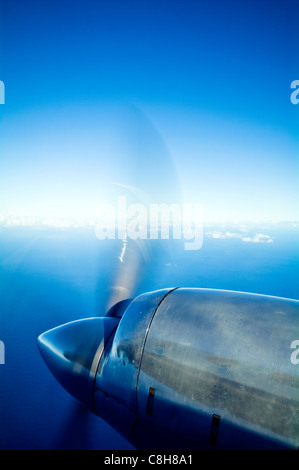 A chrome engine and propellor of a plane flying over tropical islands. Stock Photo