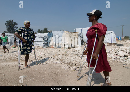 Women walks with crutches at a makeshift camp for survivors of a 7.0 magnitude earthquake which struck Haiti on 12 January 2010 in Port-au-Prince Stock Photo