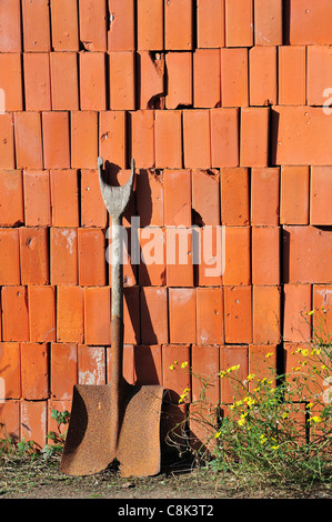 Shovel and pile of stacked red bricks as building material at brickworks, Boom, Belgium Stock Photo