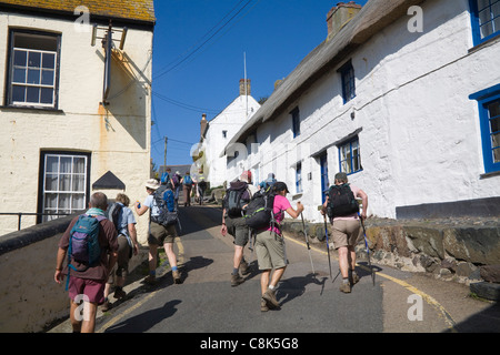 Cadgwith Cornwall England Group ramblers leaving picturesque fishing village up steep hill Stock Photo