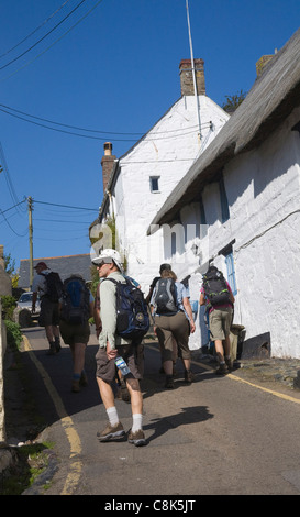 Cadgwith Cornwall England Group ramblers leaving picturesque fishing village up steep hill Stock Photo