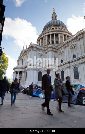 Passers-by walk past the anti-capitalist protesters' camp outside St Paul's Cathedral, London, October, 2011. Stock Photo