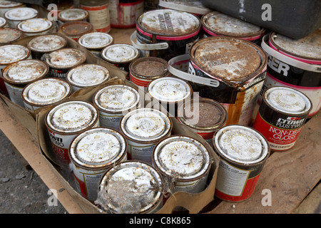 pile of old crown tins of paint rusting and covered in dirt in an old factory warehouse unit belfast northern ireland uk Stock Photo