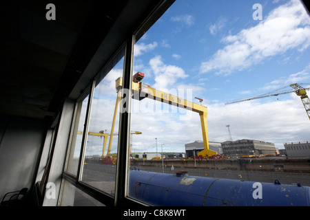 looking out at harland and wolff shipyard cranes from inside an old factory warehouse unit belfast northern ireland uk Stock Photo