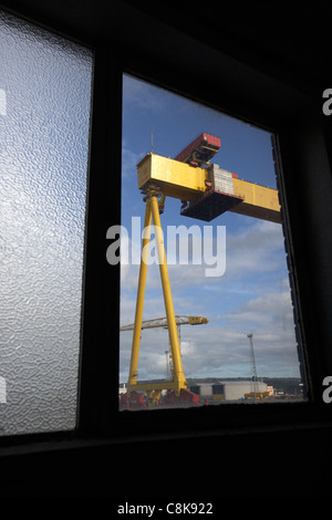 looking out at harland and wolff shipyard cranes from inside an old factory warehouse unit belfast northern ireland uk Stock Photo