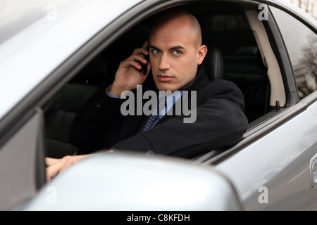 Bald businessman making call from car Stock Photo