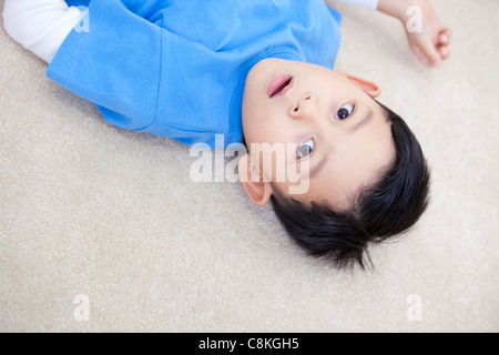 Surprised Chinese boy lying on the floor Stock Photo