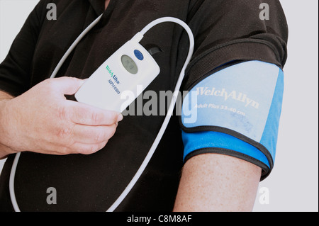 24 hour blood pressure monitoring unit taking readings every half an hour on a middle aged man Stock Photo