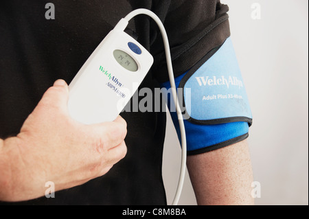 24 hour blood pressure monitoring unit taking readings every half an hour on a middle aged man Stock Photo