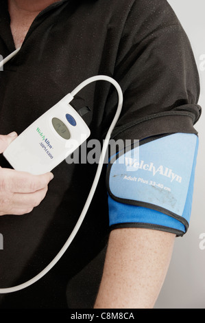 24 hour blood pressure monitoring unit taking readings every half an hour on a middle aged man Stock Photo